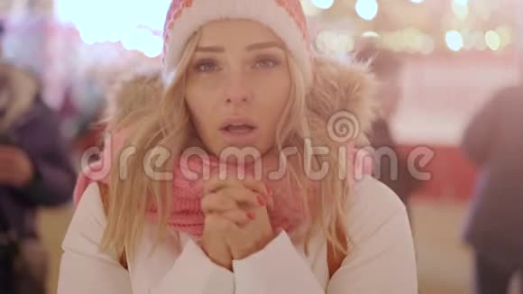 可爱的微笑的年轻女子在下雪的夜晚感到寒冷和温暖的双手视频的预览图
