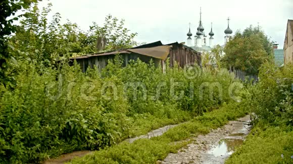 俄罗斯苏兹达尔一个小村庄的旧房子和前景的湿路背景上的大教堂视频的预览图