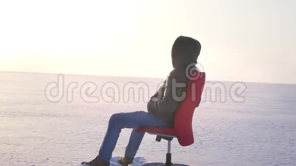 围着坐在红色椅子上的一个商人的镜头在雪地背景上看着远处视频的预览图