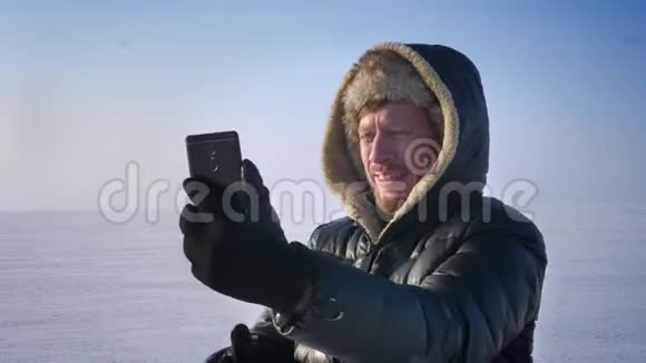 商人在智能手机上愉快地使用视频电话交谈并转身在雪地沙漠中展示背景视频的预览图