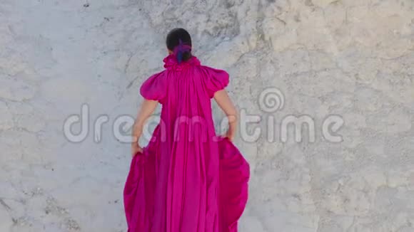 年轻的高个子女孩模特穿着一件紫色的长裙尾巴留在山上视频的预览图
