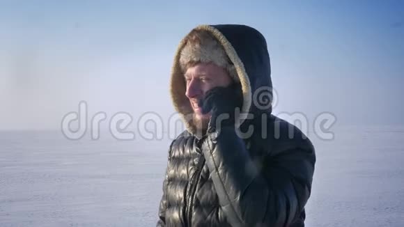 穿着保暖外套戴着头巾的商人在雪地里用手机和笑声说话的特写照片视频的预览图