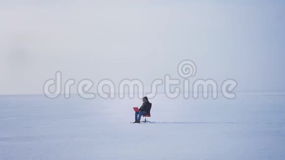 一个商人独自坐在雪地里手提电脑成功后举起双手视频的预览图