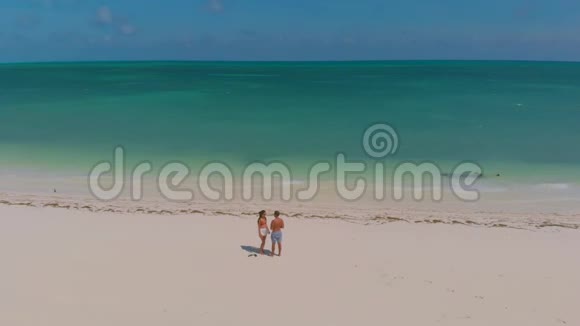 从上面看布格苏克岛上的蓬塔空中拍摄的旅行情侣漫步一望无际的白色沙滩周围是绿松石视频的预览图