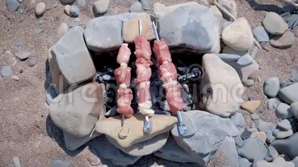 用石头手工制作的篝火上的扦子上的Shashlik烹饪上面有热炭俯视视频的预览图