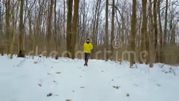 穿着黄大褂的体育健将朝镜头奔跑在白雪皑皑的冬林中视频的预览图