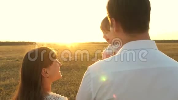 日落时分爸爸妈妈抱着一个小女儿玩耍日落时一家人和一个孩子散步父亲演奏视频的预览图