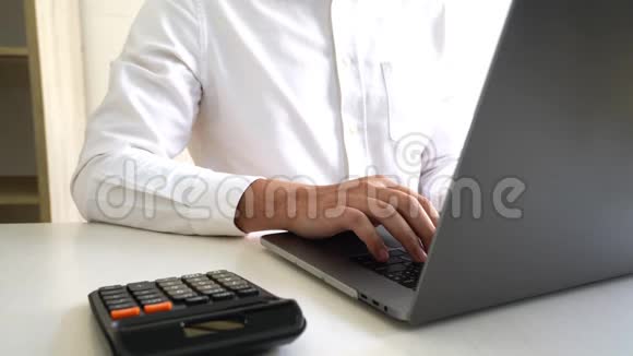 4K男子手中电脑键盘打字坐在办公桌前在家里用笔记本电脑工作的视频视频的预览图