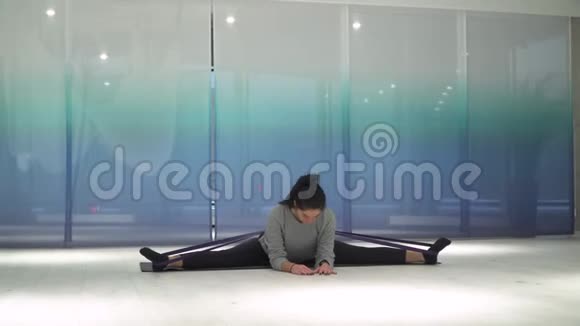 可爱的年轻女人做伸展运动使用健身口香糖和倾斜身体在不同的侧面在垫子在健身房女孩视频的预览图