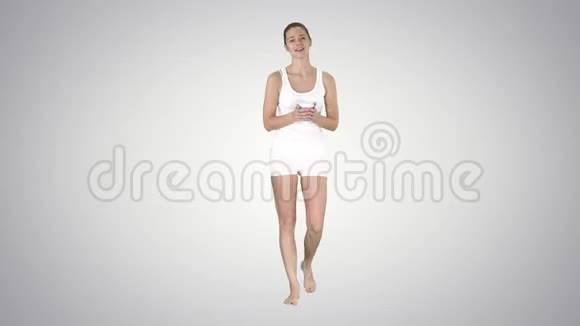 穿着渐变运动服的女人拿着一杯咖啡在渐变背景上和镜头交谈视频的预览图