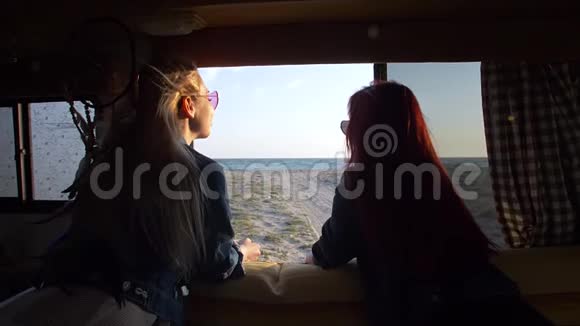两个女孩望着海岸的自动拖车窗口视频的预览图