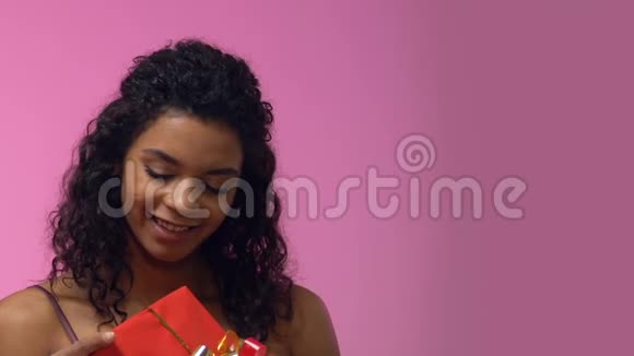 非洲裔美国妇女拿着礼品盒抬头仰望梦想着浪漫的约会视频的预览图