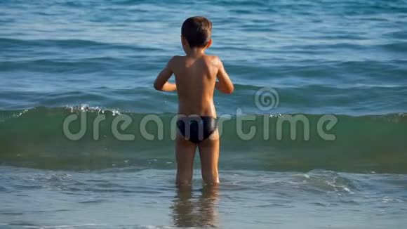 小男孩在海边的波浪上跳跃视频的预览图