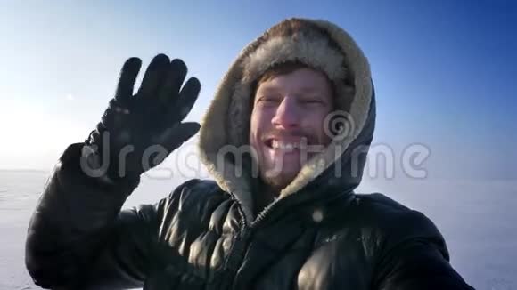 特写自拍穿着外套和引擎盖的男人的肖像录制视频在雪地沙漠中愉快地交谈视频的预览图