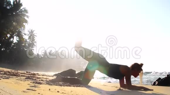 夏日阳光照耀下的沙滩上女孩剪影练习瑜伽视频的预览图