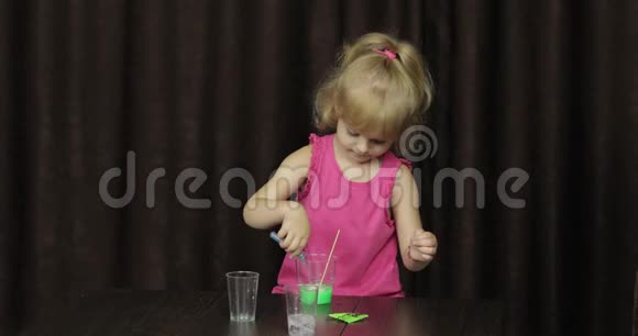 孩子们玩着做绿色黏液混合配料手做玩具的小孩视频的预览图