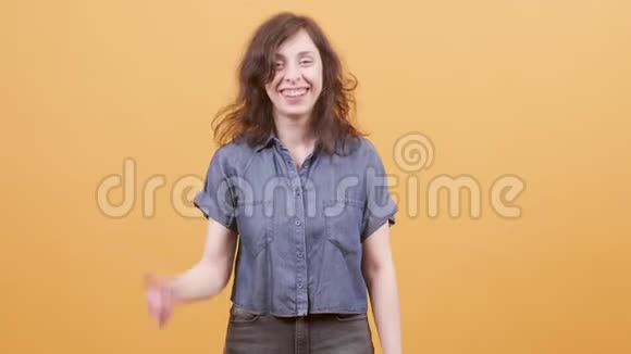 兴奋的年轻女子在黄色背景下跳舞视频的预览图