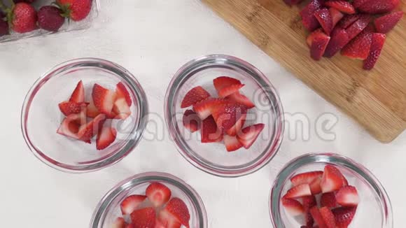 切片草莓在透明玻璃碗切片草莓在切碎板水果沙拉甜点草莓果冻准备视频的预览图