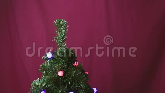 一个年轻人用一个红色闪亮的球装饰圣诞树视频的预览图