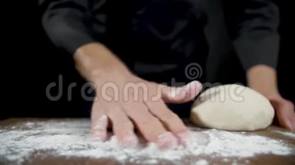 厨师在黑色背景的木桌上铺面粉视频的预览图