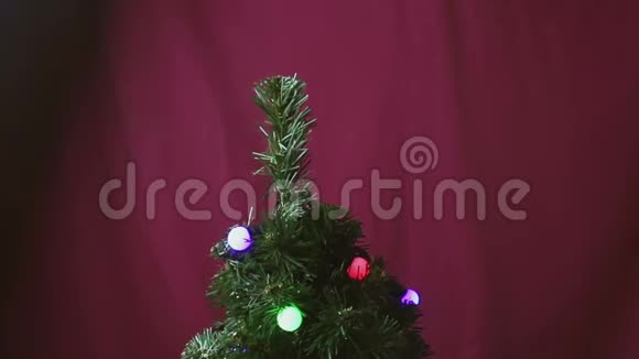 一个年轻人用一个红色闪亮的球装饰圣诞树视频的预览图