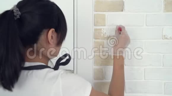 在公寓或房子里用刷砖墙画的女人的特写视频的预览图