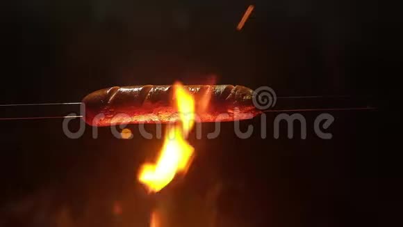 用扦子刺穿的全景浅汁香肠挂在炽热的火焰上大量的火火苗上的香肠视频的预览图