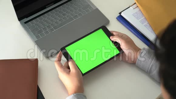 商务男士手拿平板电脑在办公室绿色桌面屏幕上的4k视频视频的预览图