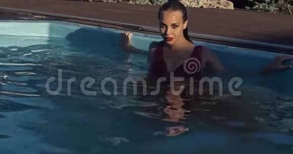 穿着红色裙子的性感年轻女子正在泳池边摆姿势4K视频的预览图