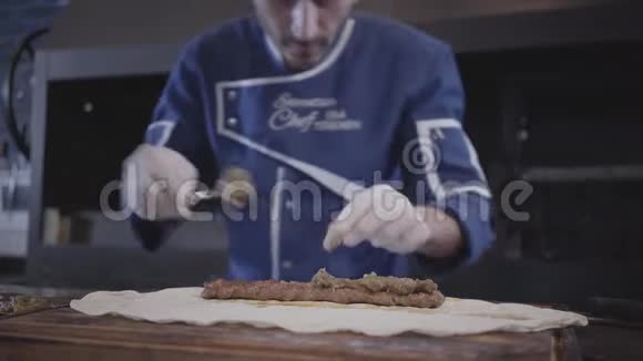 穿着蓝色厨师制服的熟练男子在现代餐厅烹饪卢拉串厨师把面包放在烤碎肉上视频的预览图