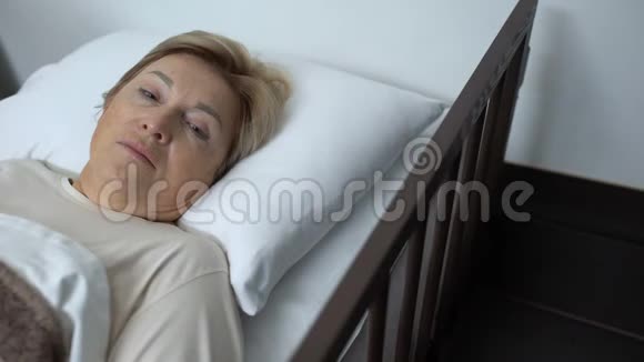 躺在病床上的老年女性心烦意乱用颤抖的手触摸额头视频的预览图