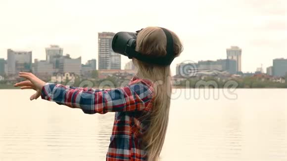金发女孩留着长发和眼镜VR站在大城市附近的海边高清1080视频的预览图