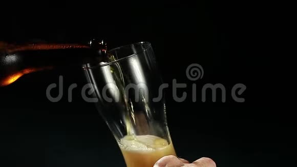 啤酒是从黑色背景的瓶子里倒入玻璃杯的视频的预览图