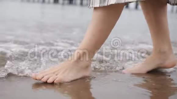 日落时分女人的脚在金色的沙滩上走得很近女腿沿着沙滩行走视频的预览图