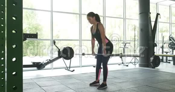强壮漂亮的女人在运动俱乐部用杠铃训练肌肉现代体育运动中的女运动员视频的预览图