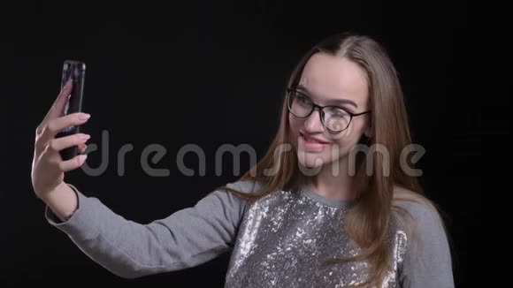 年轻迷人的时髦女性戴着眼镜的特写镜头带着自拍带着欢快的视频的预览图