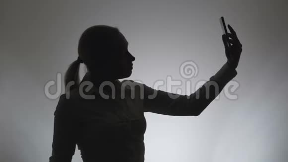 白色背景的女人的剪影一个女人用智能手机里的照相机拍照视频的预览图