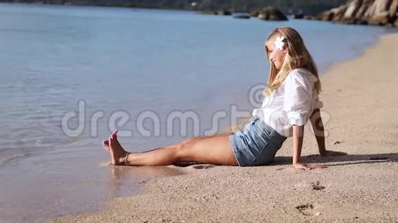 一个漂亮的金发女人坐在海滩上视频的预览图