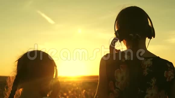 快乐的十几岁的女孩在公园美丽的夕阳下听音乐跳舞戴着耳机的儿童视频的预览图