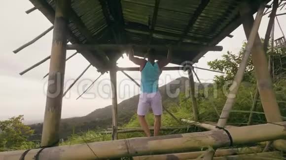 热带森林中的健身男子训练在水平杆上拉锻炼运动员在做拉力锻炼视频的预览图