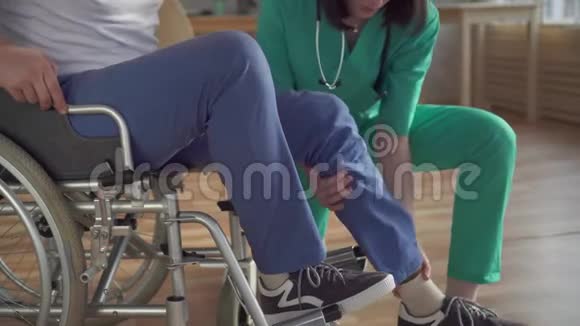 贴身女护士帮助残疾人从轮椅上站起来视频的预览图