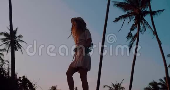 穿着连衣裙戴着帽子在热带海滩放松视频的预览图