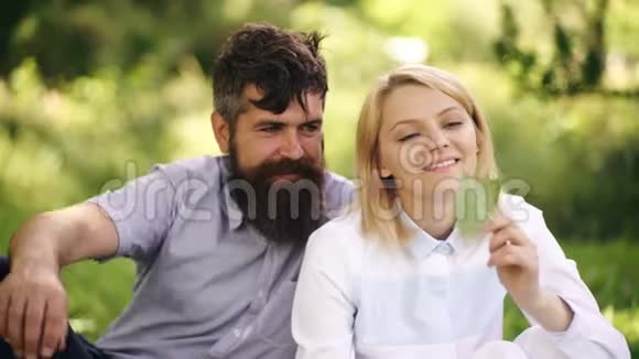 幸福的微笑夫妇在绿草上放松公园躺在草地上的年轻家庭保健自由爱视频的预览图
