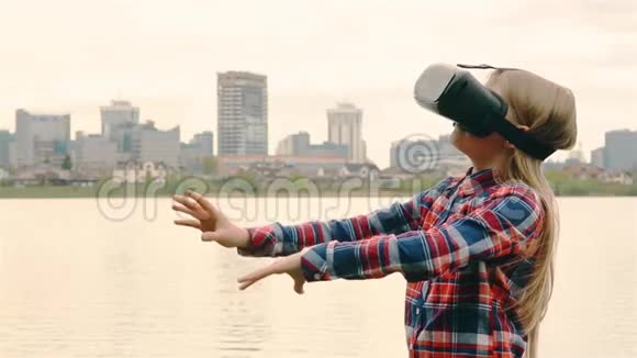 一位金发女孩戴着VR耳机背景是一座靠近大海的大城市HD1920视频的预览图