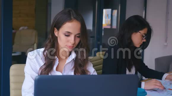 年轻漂亮的商务女性在现代的办公桌上使用笔记本电脑时会感到快乐的微笑和寻找相机视频的预览图