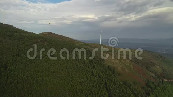 跳伞者靠近山顶的风力涡轮机飞过绿树视频的预览图