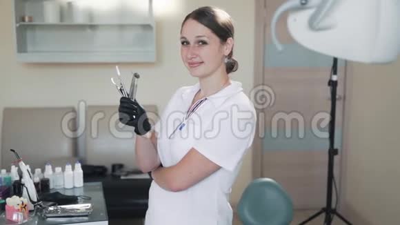 微笑的女牙医手里拿着牙科治疗工具动作缓慢视频的预览图
