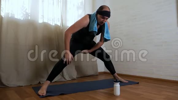 有趣的胖子正试图在地毯上做瑜伽练习穿紧身衣服的男性瑜伽士视频的预览图