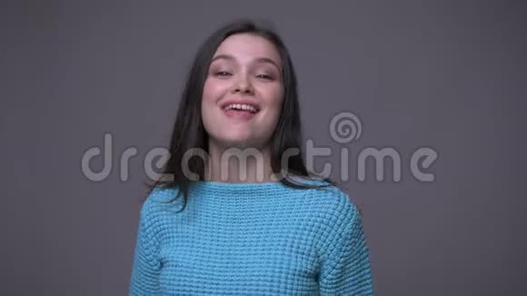 年轻的深色头发的年轻女性带着自信地抚摸着镜头背景与灰色隔离视频的预览图