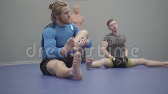 专业人士坐在地板上在健身房伸腿视频的预览图